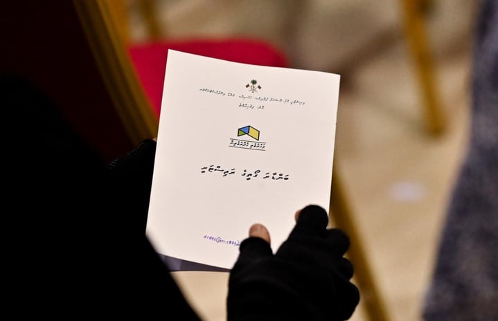 A person holding up a land registry issued under the previous government's Binveriya scheme. -- Photo: Fayaz Moosa | Mihaaru